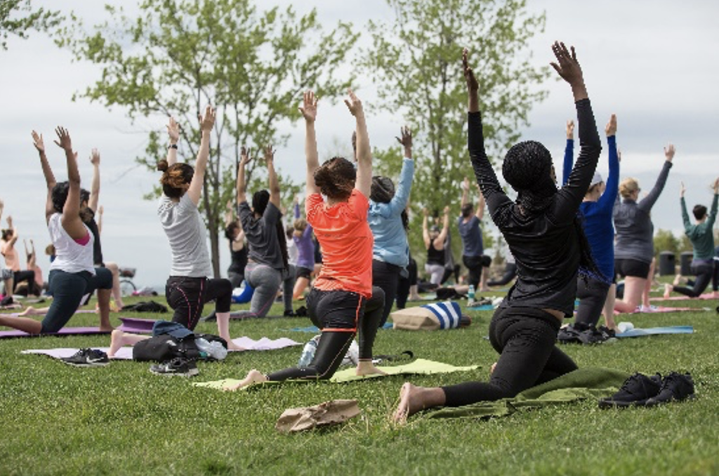 Groupe de personnes faisant des étirements de yoga dans le parc. 