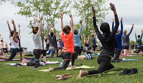Groupe de gens pratiquant le yoga dans le parc.