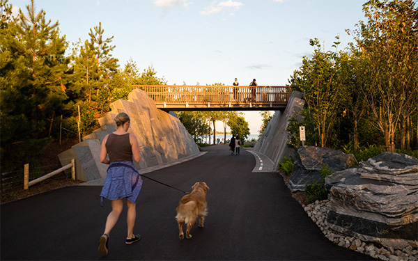 A woman running with her dog along a park pathway.
