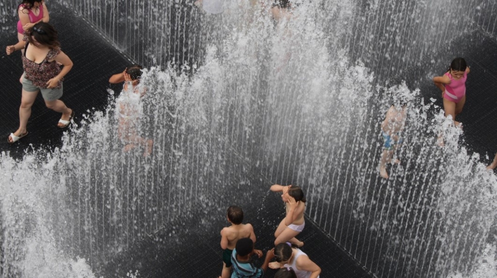 People playing in water sprouting up from the ground in an X formation