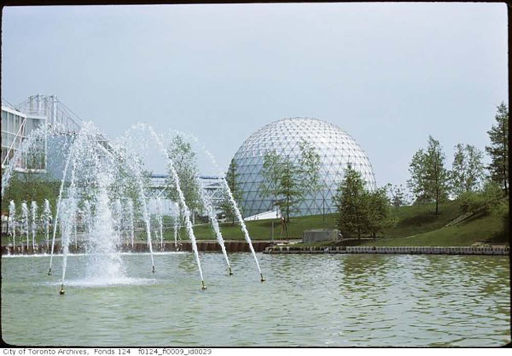 Vieille photo d’une fontaine d’eau avec les pavillons et la Cinésphère en arrière-plan. 