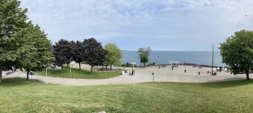 Photo of a grass area with trees abutting a paved surface with Lake Ontario on the other size of the paved surface